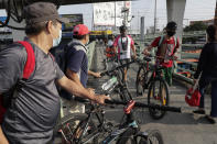 Men wearing protective masks push their bicycles at an overpass in Quezon city, Philippines, Saturday Sept. 26, 2020. Public transportation remains limited and the government orders commuters to wear face shields and face masks to help curb the spread of the coronavirus. (AP Photo/Aaron Favila)
