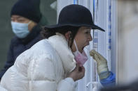 A woman has her routine COVID-19 throat swab at a coronavirus testing site in Beijing, Sunday, Dec. 4, 2022. China on Sunday reported two additional deaths from COVID-19 as some cities move cautiously to ease anti-pandemic restrictions amid increasingly vocal public frustration over the measures. (AP Photo/Andy Wong)