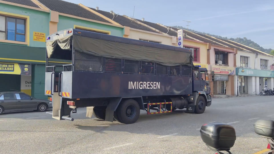 In this image taken from a video, an immigration truck with unidentified people onboard is driven on a road that leads to Lumut Naval Base Tuesday, Feb. 23, 2021 in Lumut, Malaysia. A Malaysian court Tuesday ordered a halt to the planned deportation of 1,200 Myanmar migrants to hear an appeal by two human rights groups, which say the migrants included refugees, asylum seekers and minors. (AP Photo)