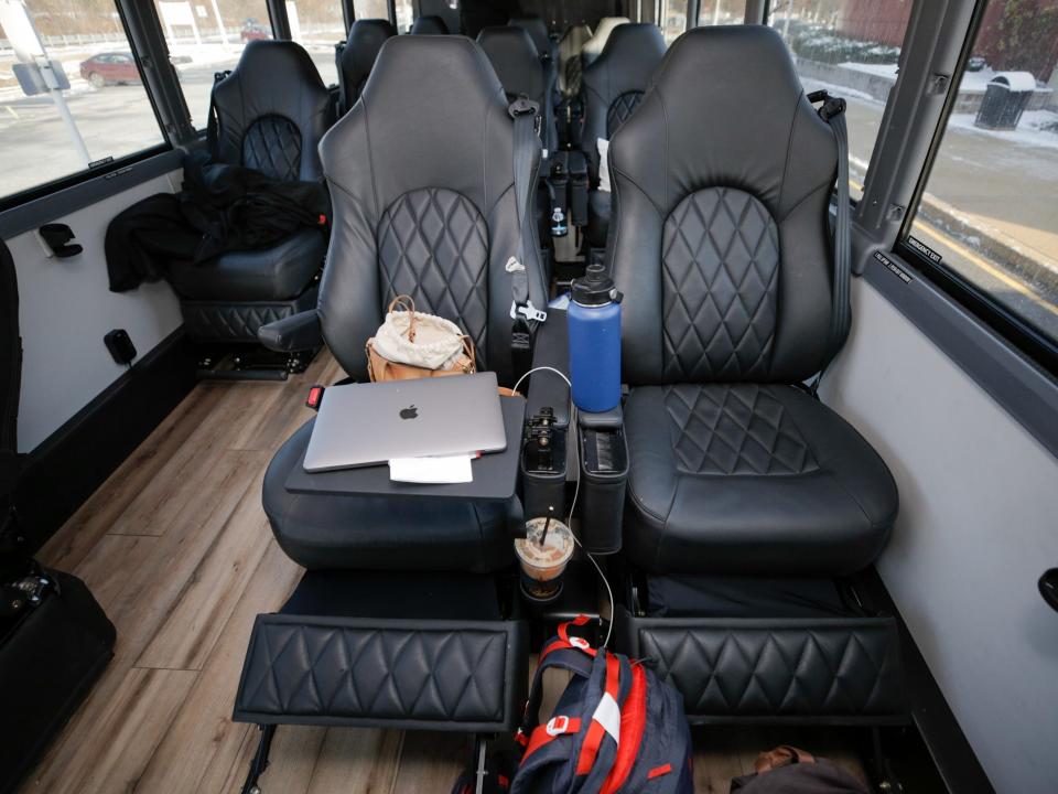 A row of two leather sets. One chair has a laptop, purse, water bottle with a backpack on the floor.