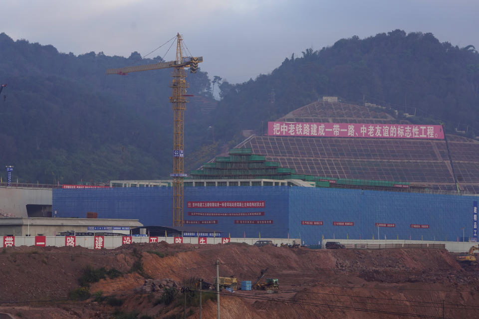 The construction site of the Pu'er high speed rail station that is part of the China-Laos railway is seen in Pu'er near a banner with the words "Make China Laos railway into One Road One Belt, China Laos Friendship Representative Project" in southwestern China's Yunnan Province on Wednesday, Dec. 2, 2020. Laos, a nation of 7 million people wedged between China, Vietnam and Thailand, is opening a $5.9 billion Chinese-built railway that links China's own poor southwest to foreign markets but piles on potentially risky debt. (AP Photo/Ng Han Guan)