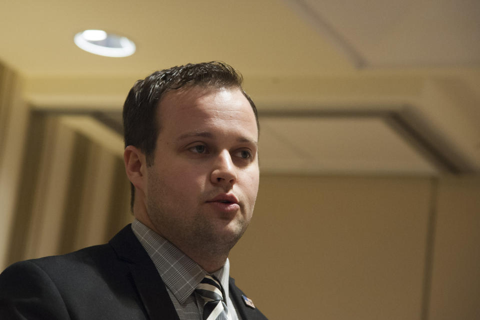 A close up photo of Josh Duggar  in a suit and tie in a generic beige conference room. (Kris Connor / Getty Images)