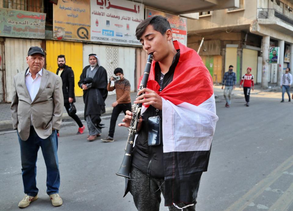 A protester plays an instrument on a street leading to Tahrir Square where ongoing anti-government protests are taking place in Baghdad, Iraq, Sunday, Dec. 8, 2019. At least 25 people, including protesters and police, were killed and 130 wounded on Friday when armed men in pick up trucks stormed Khilani square, which is adjacent to Tahrir, and shot live ammunition at demonstrators. (AP Photo/Hadi Mizban)