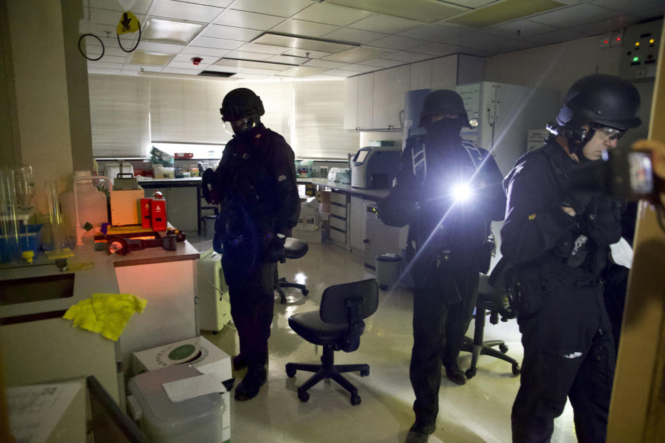 Policemen from Explosive Ordnance Disposal (EOD) unit search for dangerous materials at bio laboratory inside the Hong Kong Polytechnic University campus in Hong Kong, Thursday, Nov. 28, 2019. Police safety teams Thursday began clearing a university that was a flashpoint for clashes with protesters, and an officer said any holdouts still hiding inside would not be immediately arrested. (AP Photo/Ng Han Guan)