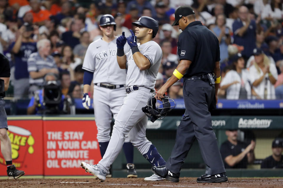 New York Yankees' DJ LeMahieu, left, looks on as Jasson Dominguez, center, celebrates after they scored on a home run by Dominguez during the inning of a baseball game against the Houston Astros, Sunday, Sept. 3, 2023, in Houston. Umpire Jeremie Rehak, right, looks on. (AP Photo/Michael Wyke)