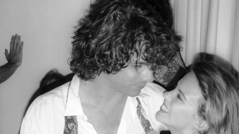 A black-and-white photo of Michael Hutchence embracing Kylie Minogue at a party