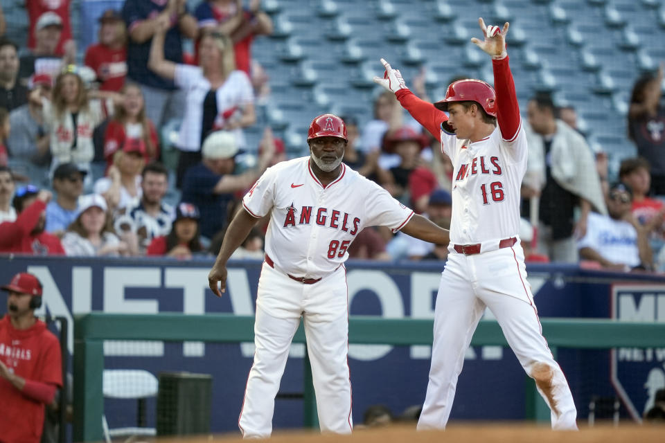 Los Angeles Angels' Mickey Moniak, right, celebrates after his two-run triple with third base coach Eric Young Sr., left, during the second inning of a baseball game against the Texas Rangers, Monday, July 8, 2024, in Anaheim, Calif. (AP Photo/Ryan Sun)