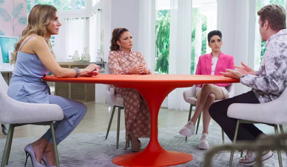 The Estefans and Perez sitting around a red table