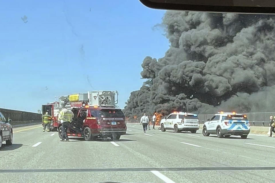 This photo provided by Angelique Feliciano shows firefighters and police responding after a crash involving a fuel truck and a car sparked a fire on the Gold Star Bridge between New London and Groton, Conn., on Friday, April 21, 2023. The crash closed Interstate 95 in both directions during the blaze. (Angelique Feliciano via AP)