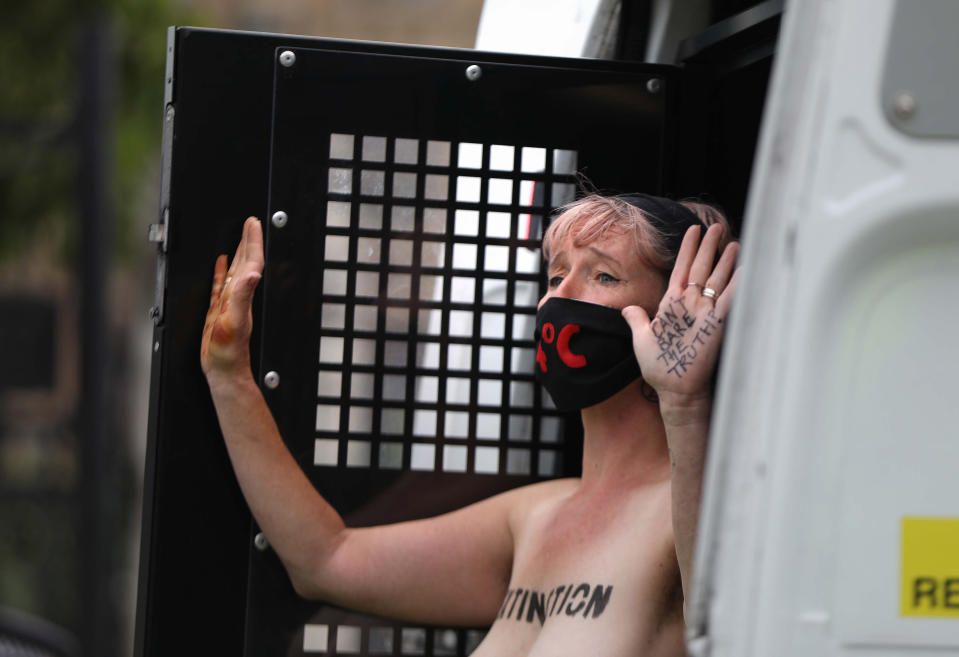 Police detain a topless Extinction Rebellion protester outside the Houses of Parliament, London, on the last day of demonstrations.