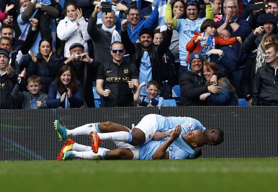 Manchester City's captain Vincent Kompany (L) celebrates with teammate Yaya Toure after scoring against West Ham United during their English Premier League soccer match at the Etihad Stadium in Manchester, northern England May 11, 2014. REUTERS/Darren Staples (BRITAIN - Tags: SPORT SOCCER) FOR EDITORIAL USE ONLY. NOT FOR SALE FOR MARKETING OR ADVERTISING CAMPAIGNS. NO USE WITH UNAUTHORIZED AUDIO, VIDEO, DATA, FIXTURE LISTS, CLUB/LEAGUE LOGOS OR "LIVE" SERVICES. ONLINE IN-MATCH USE LIMITED TO 45 IMAGES, NO VIDEO EMULATION. NO USE IN BETTING, GAMES OR SINGLE CLUB/LEAGUE/PLAYER PUBLICATIONS