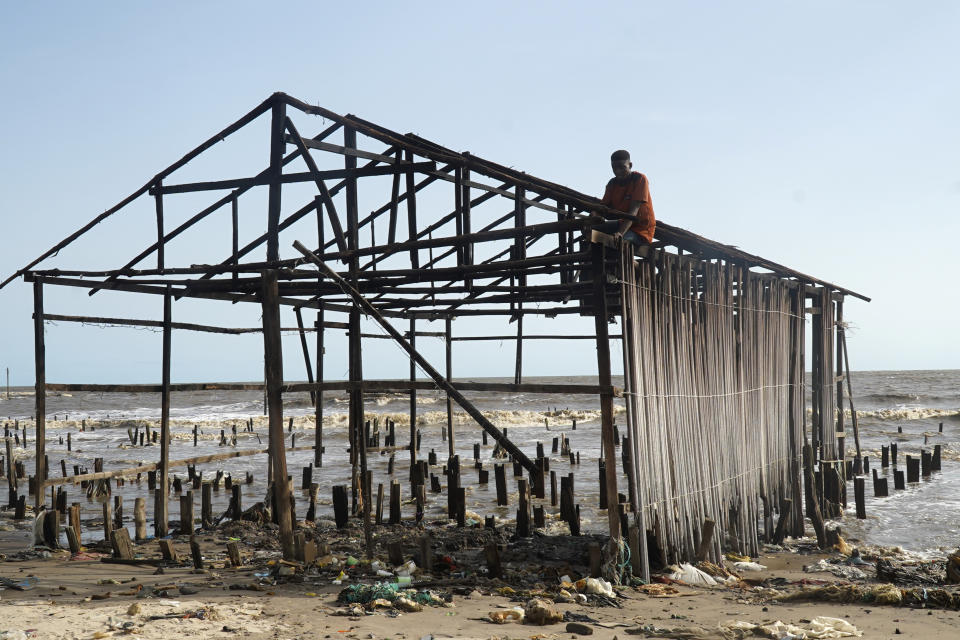 A man salvages wood from a damage stilt house following a coastal erosion in Ayetoro, Southwest Nigeria, Friday, April 5, 2024. Ayetoro, a coastal community more than 200 km southeast of Nigeria's business capital Lagos, has been experiencing coastal erosion for many years. But the changes have recently rapidly worsened with the community slumping into the Atlantic Ocean, leading to repeated displacements of households and businesses. (AP Photo/Dan Ikpoyi)