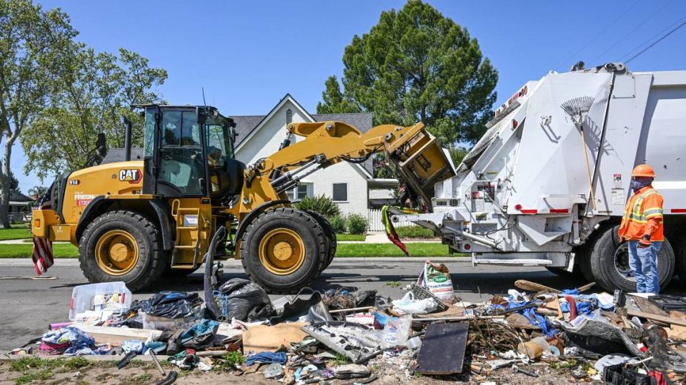 Un trabajador de la ciudad utiliza "la garra" cargador frontal para recoger la basura residencial dejado fuera en una calle en el sureste de Fresno durante la Operación Limpieza en Fresno el lunes, 8 de abril 2024. CRAIG KOHLRUSS/ckohlruss@fresnobee.com