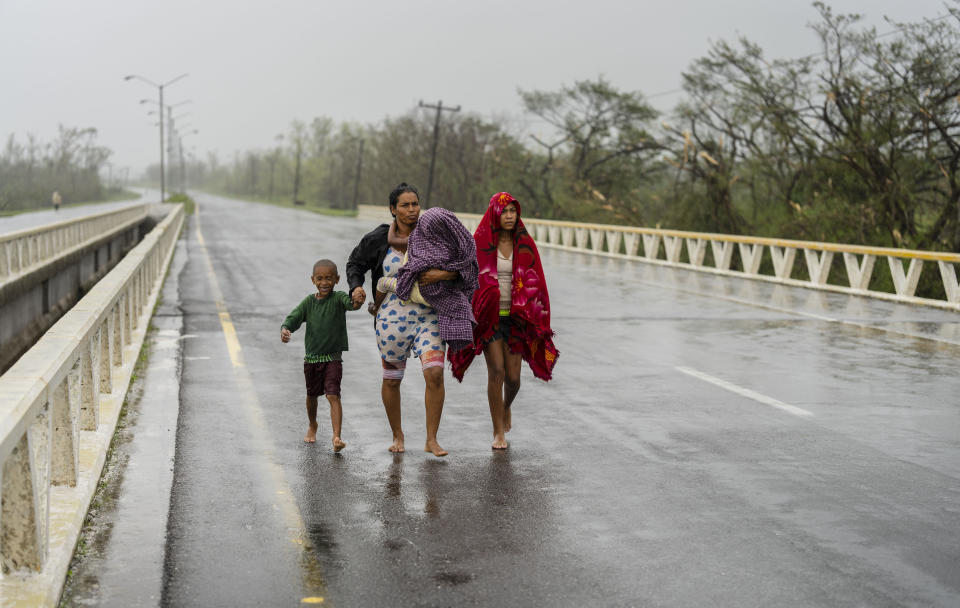 Una familia camina bajo la lluvia en busca de refugio luego de que el huracán Ian anegó su vivienda en Pinar del Río, Cuba, el 27 de septiembre de 2022. (AP Foto/Ramón Espinosa)