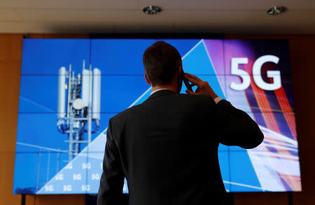 An employee of Germany's Federal Network Agency (Bundesnetzagentur) uses his mobile phone in front of a screen set up for the auction of spectrum for 5G services at the Bundesnetzagentur headquarters in Mainz, Germany, March 18, 2019. REUTERS/Kai Pfaffenbach