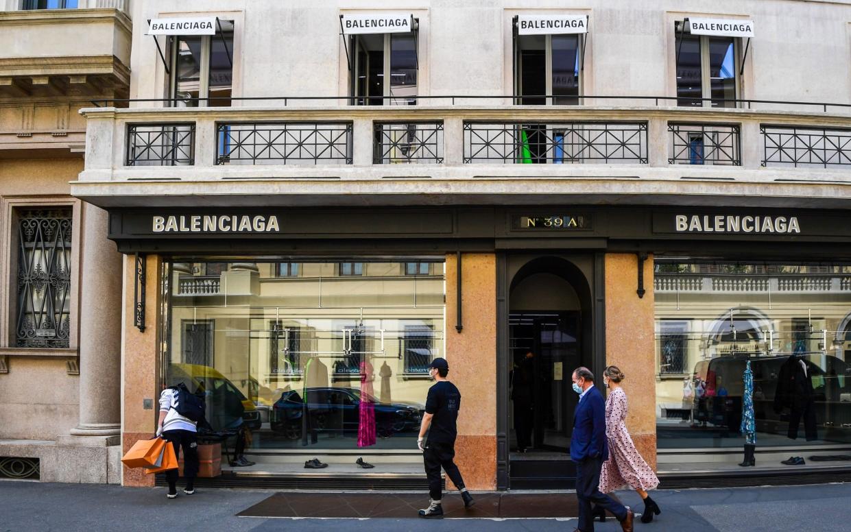 People walk past a Balenciaga shop on May 18, 2020 in central Milan, Italy - Miguel Medina/AFP