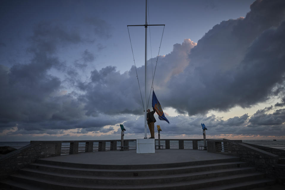 ARROMANCHES-LES-BAINS, FRANCE - JUNE 06: Adrian Cox, a British Expat and Councilor of Arromaches, raises the flag of the Normandy Veterans Association at dawn to commemorate the 76th Anniversary of the D-Day landings at dawn on Gold Beach on June 06, 2020 in Arromanches-les-Bains, France. Due to Covid-19 travel restrictions this is the first time in 75 years that veterans have not been able to attend the Anniversary.  (Photo by Kiran Ridley/Getty Images)