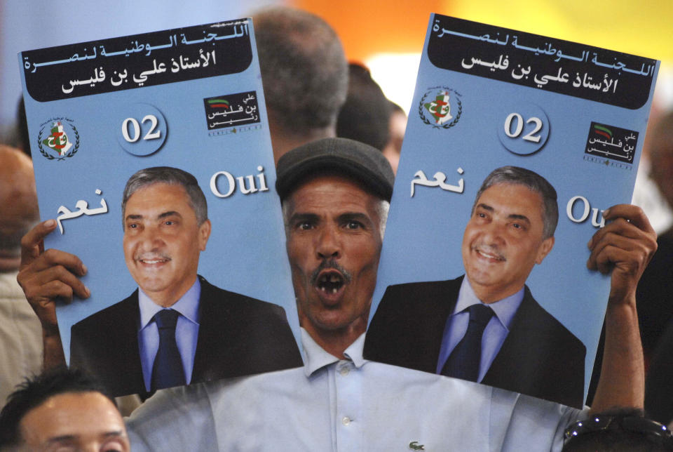 In this April 13, 2014 photo made available April 14, a supporter of Algerian presidential candidate Ali Benflis holds posters of the Benflis during his election campaign rally in Rouiba, east of Algiers, Algeria. Benflis is seen as the only real rival to incumbent President Abdelaziz Bouteflika for the upcoming presidential election. Six candidates are running for the powerful presidency in the April 17 elections. (AP Photo/Sidali Djarboub)