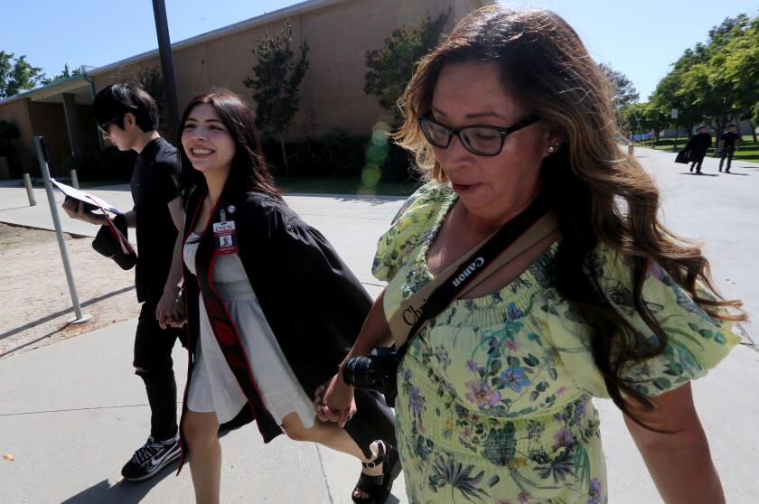 NORTHRIDGE, CALIF. - MAY 22, 2022. Audrie Gomez, center, tours the campus of California State University Northridge before graduation ceremonies on Sunday, May 22. 2022, with her mother Ruthie Gomez and boyfriend Jae Young. Audrie's father, Robert Gomez, was a facililites maintainance employee at California State University Northridge before he died. He installed a water fountain on campus for Audrie, who graduated with bachelors degree in journalism. Her dad recently succumbed to cancer. The water fountain is near the school newspaper offices where Audrie worked. (Luis Sinco / Los Abngeles Times)