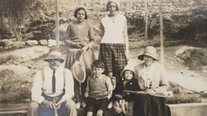 Arthur Ransome, wearing a white shirt, black tie and hat, in the 1920s in Aleppo with some of the Altounyan children.