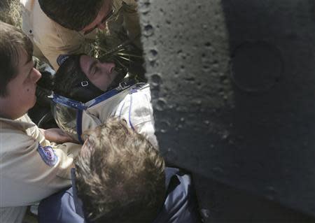 Russia's space agency ground personnel help US astronaut Chris Cassidy to get out of the Soyuz TMA-08M space capsule sortly after it landed some 146 km southeast of the town of Zhezkazgan in Kazakhstan, September 11, 2013. REUTERS/Maxim Shipenkov/Pool