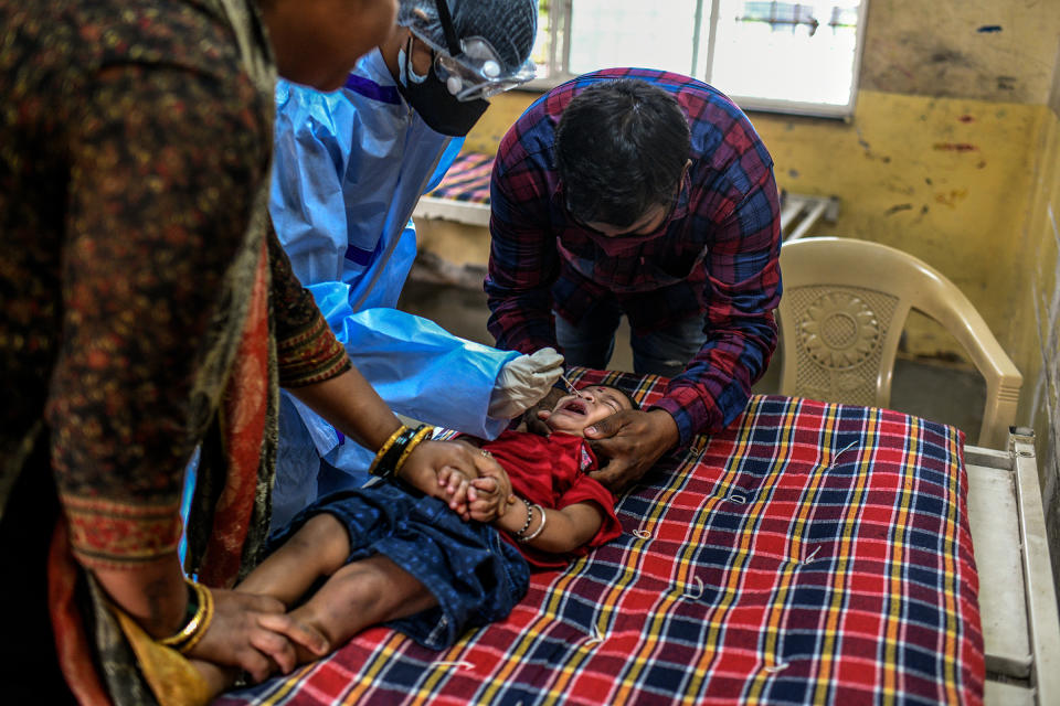 Parents keep their child still while a health care worker takes a nasal swab for a COVID-19 test at a school in Pune.<span class="copyright">Atul Loke for TIME</span>