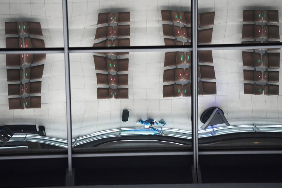 A marked seating and a janitor is reflected on ceiling tiles at the Suvarnabhumi airport in Bangkok, Thailand, Wednesday, July 21, 2021. The Civil Aviation Authority of Thailand has ordered a halt to all domestic flights operating from the most severely affected provinces effective Wednesday. Exceptions are allowed for flights to destinations that are part of a plan that allows vaccinated travelers from abroad to stay for two weeks on popular islands such as Phuket and Samui without quarantine confinement. (AP Photo/Sakchai Lalit)