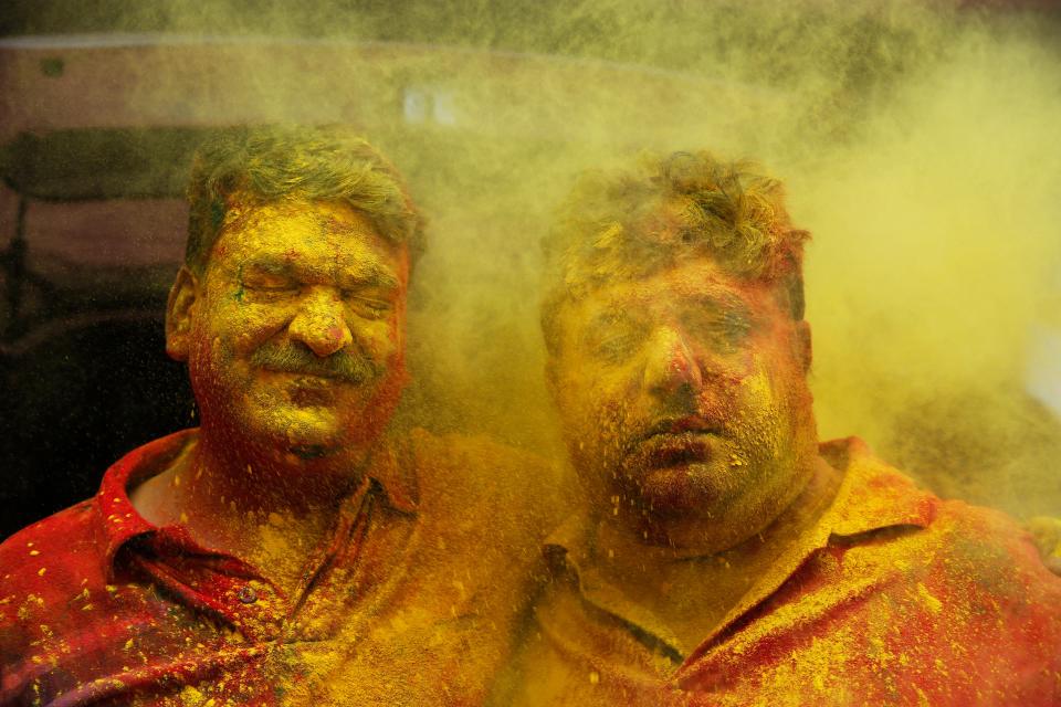 Indian men react as colored powder is thrown on their faces during celebrations marking Holi, the Hindu festival of colors, in Prayagraj, India, March 10, 2020.