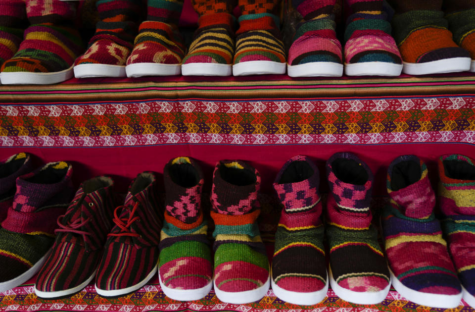 Los zapatos hechos con tejidos al estilo andino se exhiben en un taller artesanal en El Alto, Bolivia, el jueves 23 de junio de 2022. El artesano y zapatero Lidio Herbas, ha utilizado coloridos y cálidos tejidos indígenas quechua y aymara para fabricar zapatos con diseños juveniles para mitigar el frío de invierno. (AP Foto/Juan Karita)