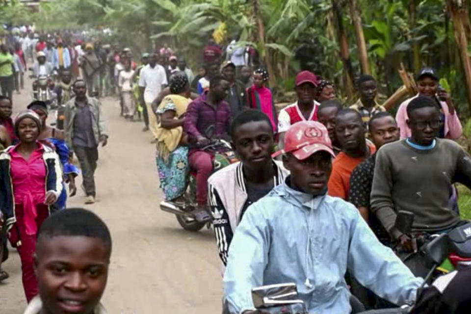 In this image made from video, people make their way towards the Lhubiriha Secondary School following an attack on the school near the border with Congo, in Mpondwe, Uganda, Saturday, June 17, 2023. Ugandan authorities recovered the bodies of dozens of people including students who were burned, shot or hacked to death after suspected rebels attacked the school, the local mayor said Saturday. (AP Photo)