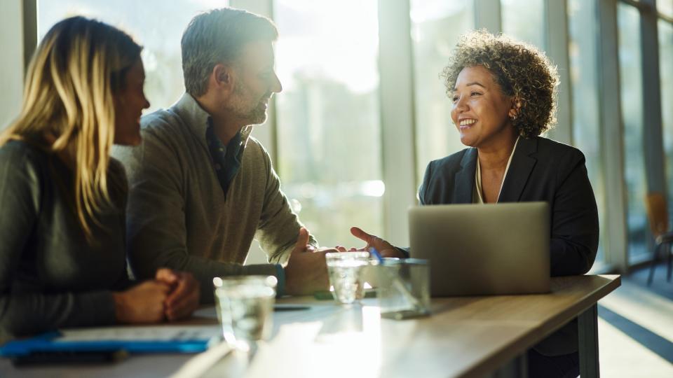  Cheerful financial adviser communicating with a couple during a meeting in an office. 