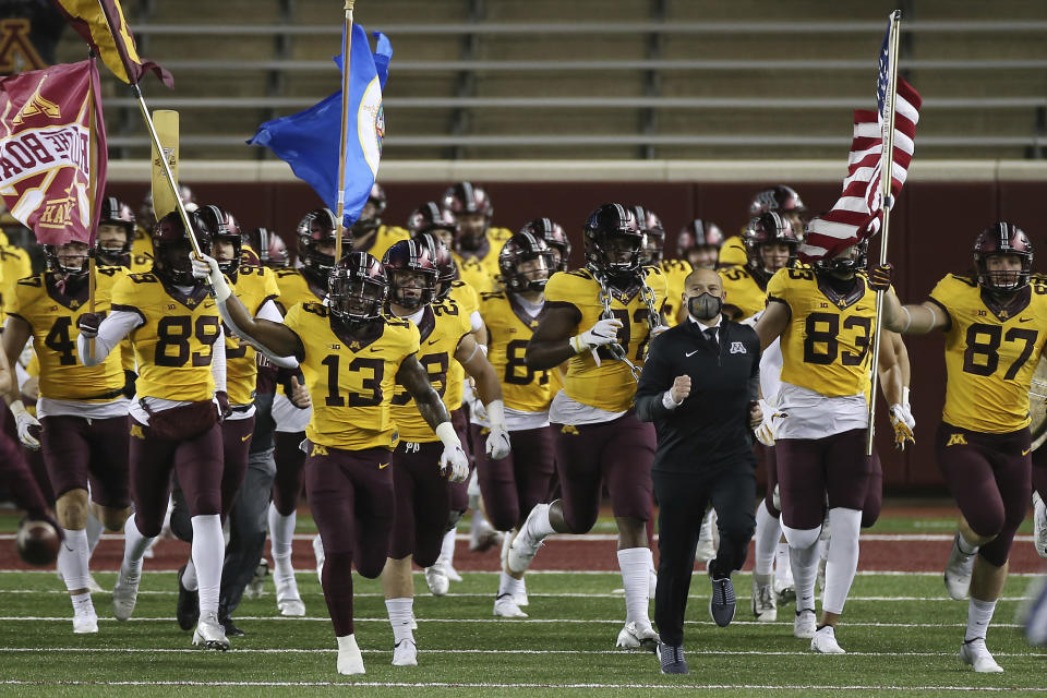 FILE - In this Friday, Nov. 20, 2020, file photo, Minnesota head coach P.J. Fleck enters the stadium with the team prior to the start of an NCAA college football game against Purdue, in Minneapolis. Fleck spoke for many coaches nationwide in December 2020, when he noted he still hadn’t shaken the hands of about half the prospects who were about to sign with his program. Those days finally are coming to an end. The NCAA has lifted the recruiting dead period that has been in place since March 13, 2020, due to the pandemic. The NCAA returns to its usual recruiting calendar Tuesday, June 1, 2021. (AP Photo/Stacy Bengs, File)