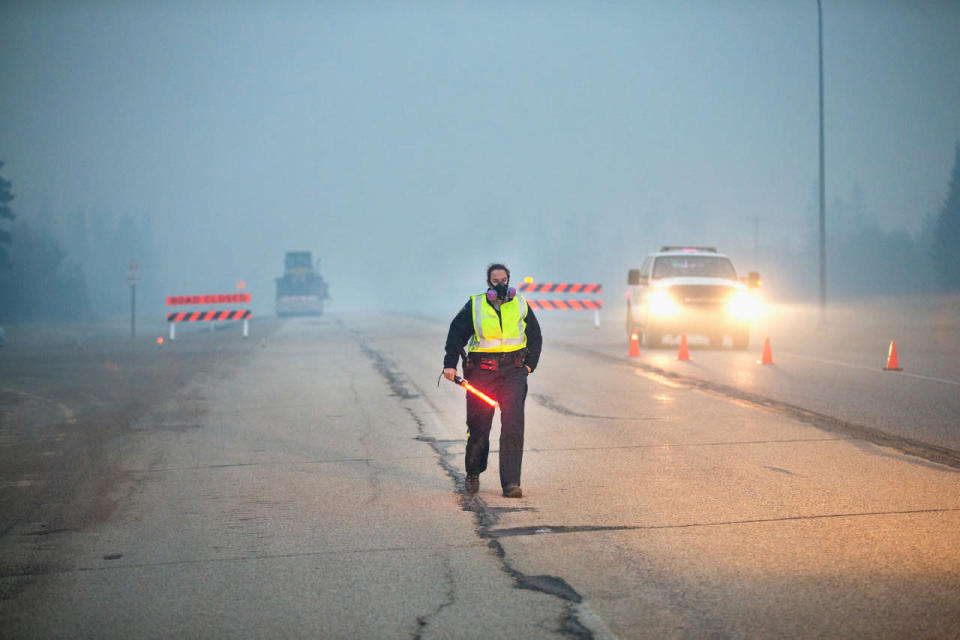 Smoke fills the air as a police officer stands guard at a roadblock along Highway 63 leading into Fort McMurray on May 8, 2016 near Fort McMurray, Alberta. (Photo by Scott Olson/Getty Images)