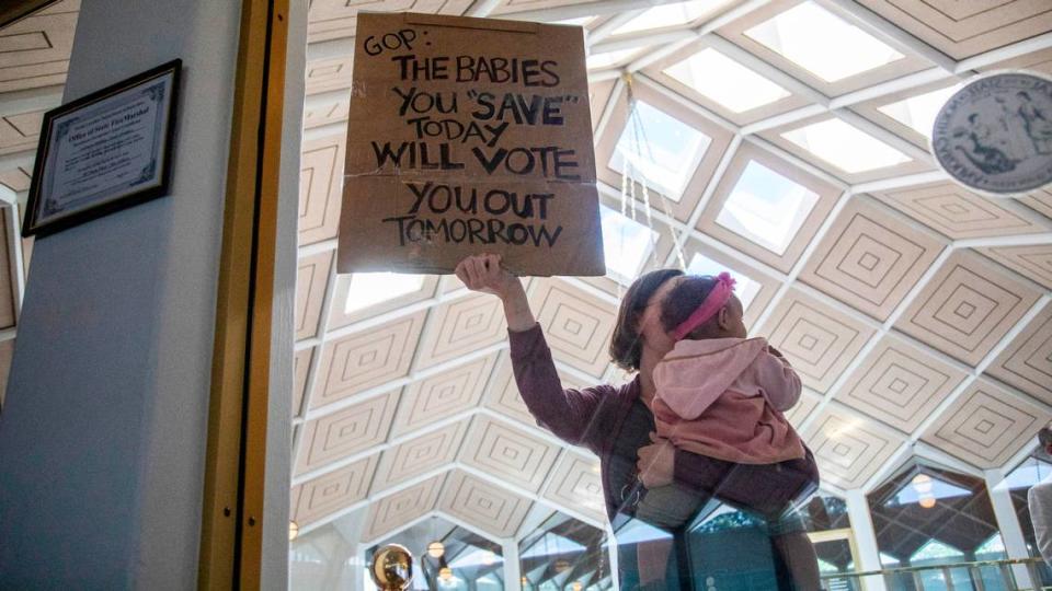 A demonstrator holds a sign and a baby outside a House Floor gallery window at the North Carolina State Legislature after Republican state lawmakers announced their plan to limit abortion rights across the state.