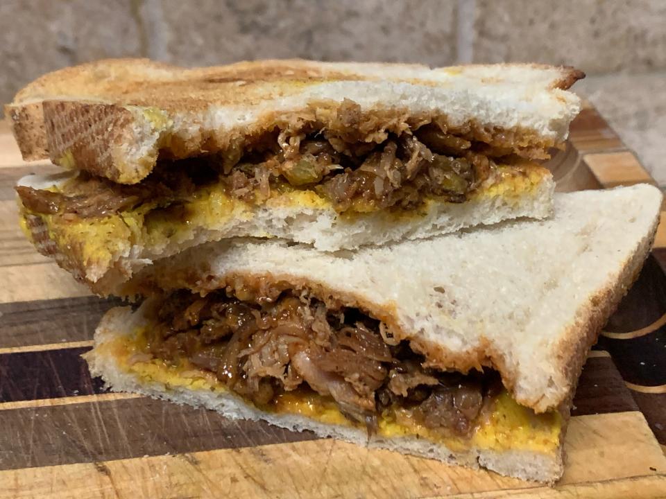 trader joe's barbecue pulled chicken on a sandwich with bright yellow mustard