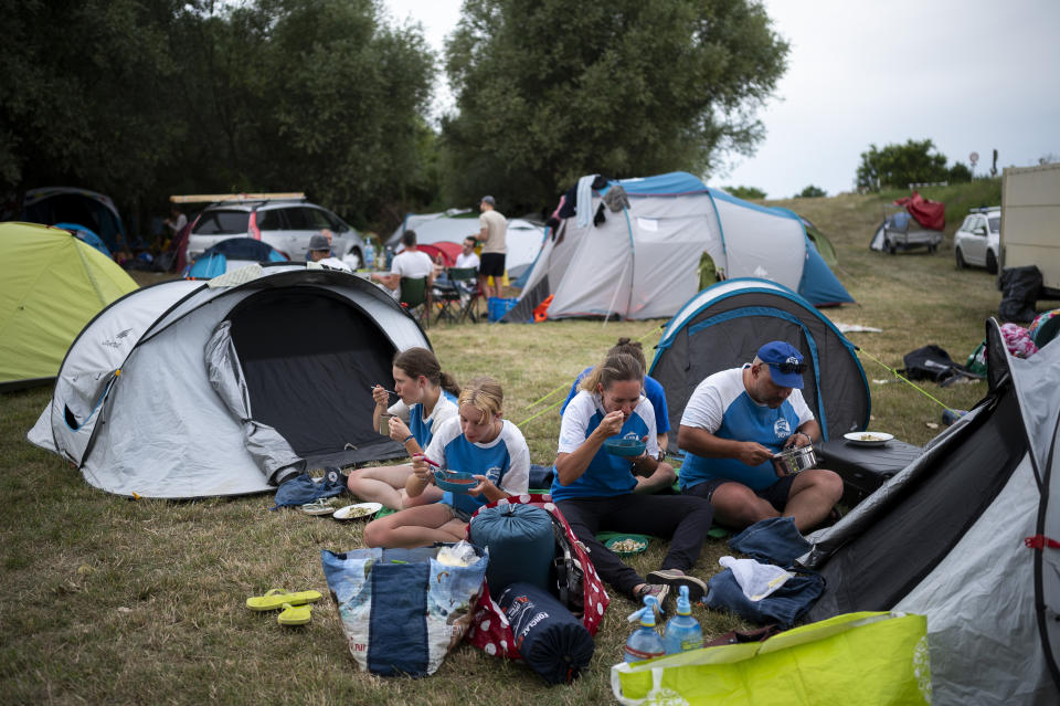 Volunteers have a dinner after a hard working day in their camp near Tiszaroff, Hungary, Tuesday, Aug. 1, 2023. The volunteers, who camp in a new spot each night as they make their way downriver, collect an average of 70 tons (around 154,000 pounds) of waste from the Tisza each year. (AP Photo/Denes Erdos)