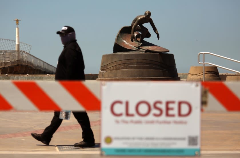 HERMOSA BEACH, CA - APRIL 23, 2020 - - The only one surfing was a statue of surfer Dewey Weber as a security guard makes sure no one walks on The Strand which has been closed to stop people from gathering to reduce the spread of the coronavirus in Hermosa Beach on April 23, 2020. Even with the warm weather the majority of beachgoers and surfers stayed away from closed beaches. The statue was created by surfing artist Phil Roberts. (Genaro Molina / Los Angeles Times)