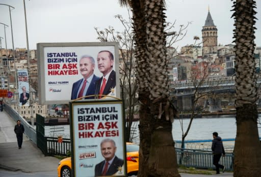 People walk past election banners of Turkish President Tayyip Erdogan and AK Party's mayoral candidate for Istanbul, Binali Yildirim, in Istanbul