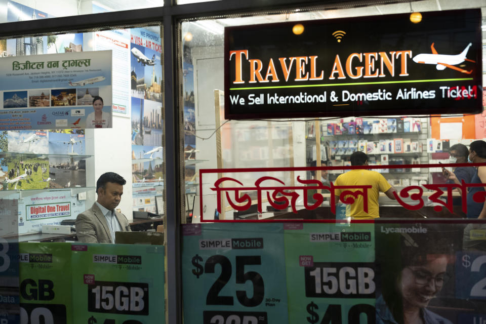 Zakaria Masud, left, works in his Queens travel agency after it reopened during the coronavirus pandemic, June 18, 2020, in New York's Jackson Heights neighborhood. "I think we're losing 50 percent of the revenue. But I think we can survive," said Masud. (AP Photo/Mark Lennihan)