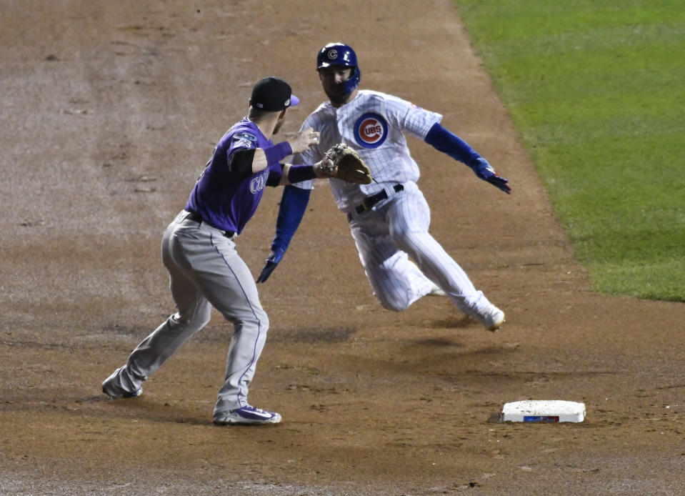 Colorado Rockies shortstop Trevor Story, left, forces out Chicago Cubs' Kris Bryant, right, at second base and throws to first base to complete a double play during the sixth inning of the National League wild-card playoff baseball game, Tuesday, Oct. 2, 2018, in Chicago. (AP Photo/David Banks)