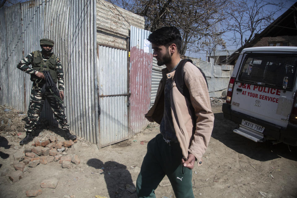 An Indian paramilitary soldier stands guard as a Kashmiri displays the insides of his clothing as he passes near the site of a shootout in Srinagar, Indian controlled Kashmir, Friday, Feb. 19, 2021. Anti-India rebels in Indian-controlled Kashmir killed two police officers in an attack Friday in the disputed region’s main city, officials said. Elsewhere in the Himalayan region, three suspected rebels and a policeman were killed in two gunbattles. (AP Photo/Mukhtar Khan)