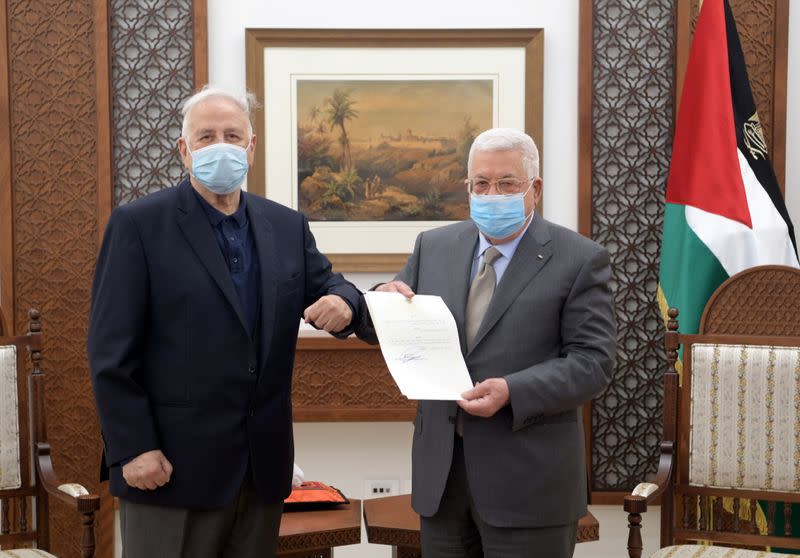 Palestinian President Mahmoud Abbas hands the election decree to Chairman of the Palestinian Central Election Committee Hana Naser in Ramallah in the Israeli-occupied West Bank