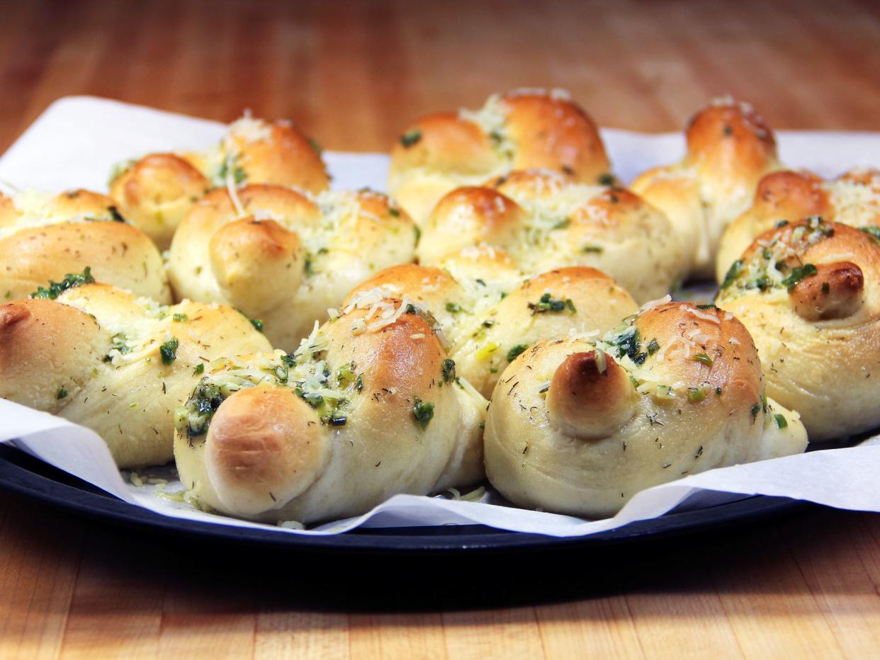 A tray of freshly baked garlic knots on parchment paper