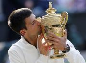 Novak Djokovic of Serbia kisses the winners trophy after defeating Roger Federer of Switzerland in their men's singles final tennis match at the Wimbledon Tennis Championships, in London July 6, 2014. REUTERS/Suzanne Plunkett