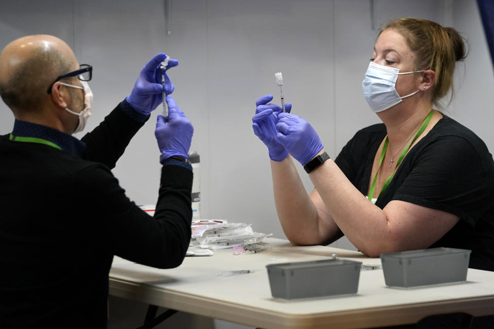 Nick Bloom, left, and Hollie Maloney, pharmacy technicians, fill syringes with Pfizer’s COVID-19 vaccine, Tuesday, March 2, 2021, at the Portland Expo in Portland, Maine. The Expo location, operated by Northern Light Health, is one of two mass vaccination sites that opened in Maine this week. (AP Photo/Robert F. Bukaty)