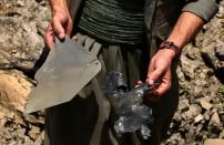 A PKK militant collects pieces of metal as he inspects a crater reportedly caused by a Turkish air strike in the Qandil mountain, the PKK stronghold in northern Iraq, on July 29, 2015