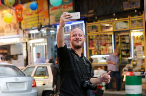 Syrian soldier Mohammad Damour takes a selfie at a street market in the capital Damascus after his discharge from the Syrian army