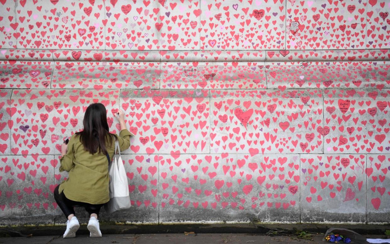 A woman leaves a message on the National Covid Memorial Wall in central London - Daniel Leal-Olivas/AFP