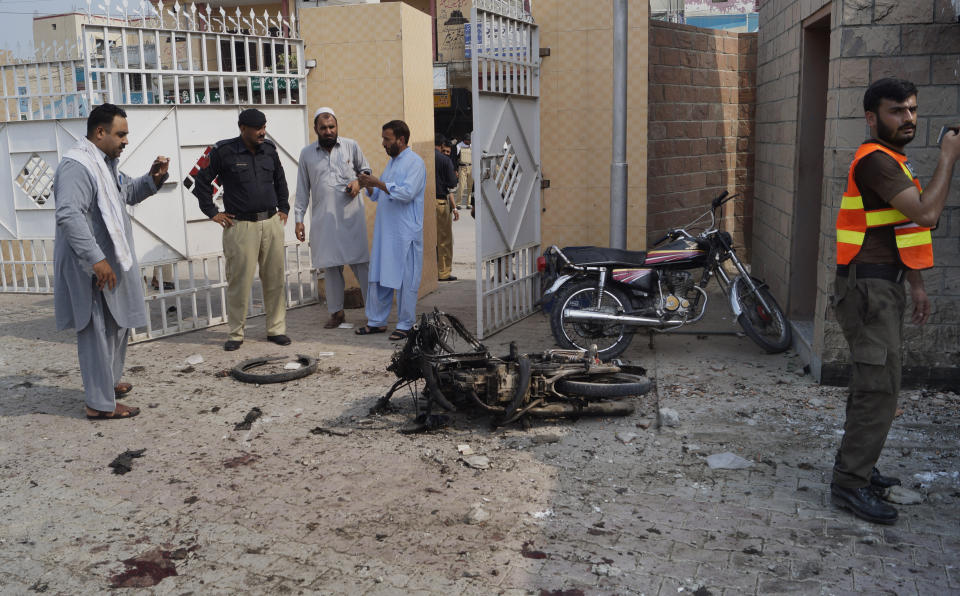 Pakistani security officials examine the site of a bombing on an entrance of a hospital in Dera Ismail Khan, Pakistan, Sunday, July 21, 2019. Police in Pakistan say gunmen opened fire on a police post and then bombed the entrance to a hospital as the wounded were being brought in.(AP Photo/Ishtiaq Mahsud)