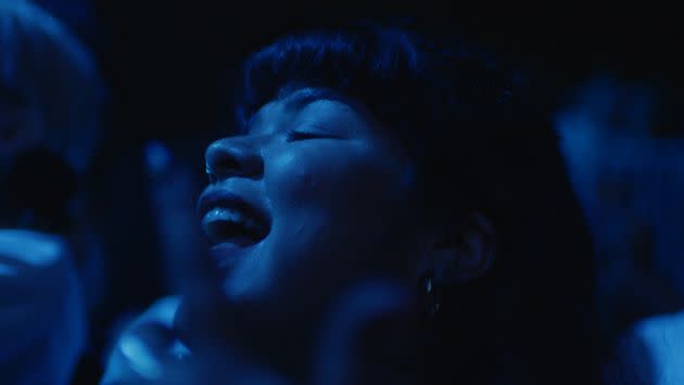 Musician and music manager Doris Muñoz dances in a blue-lit crowd at a concert in New York City, in a scene from the documentary 